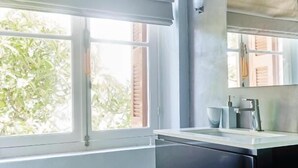 Una cocina con ventana, un lavamanos y un espejo.