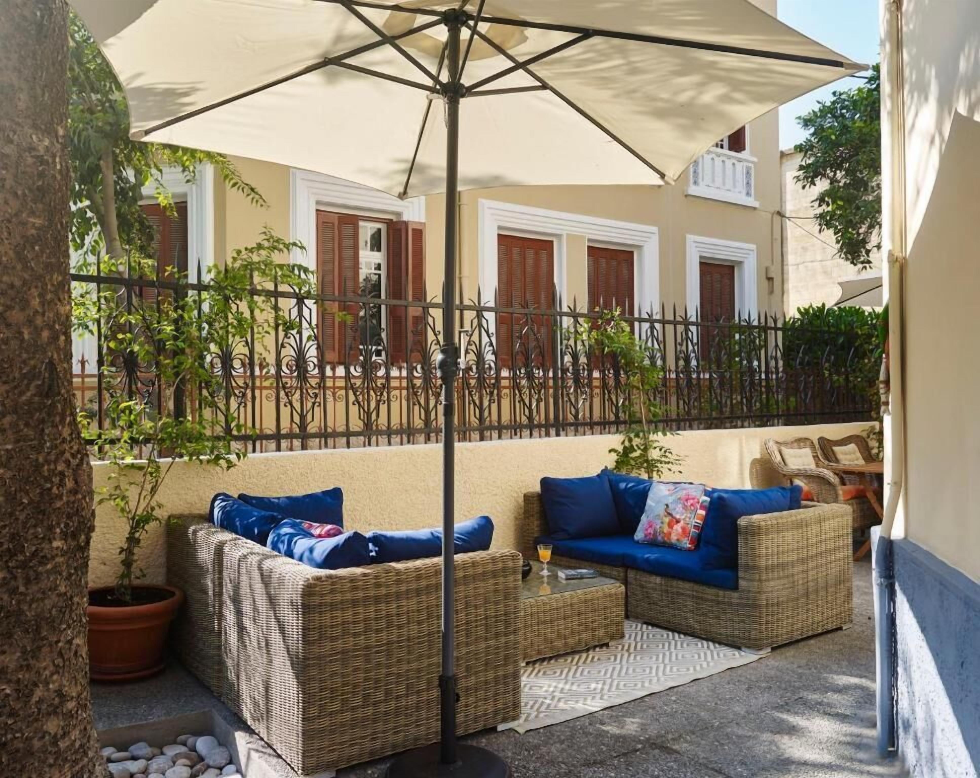 An outdoor seating area with wicker furniture, a table, and a large umbrella.