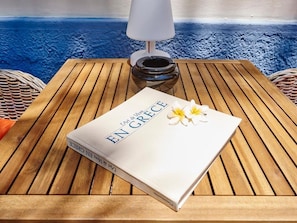A book titled 'EN GRECE' on a wooden table with a lamp and a woven basket. - Villa Sanyan - Adults Only (Rhodes)
