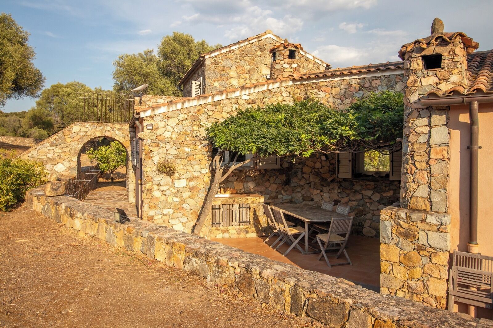 Un edificio in pietra con patio, posti a sedere all'aperto e un arco in pietra.