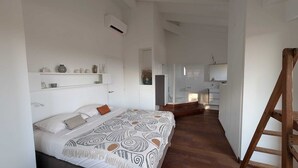 A bedroom with a bed, bedside tables, and a bathroom with a shower and bathtub. - Charming villa with ocean views and a wooded estate. (Cargèse)