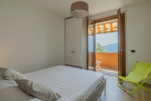 Een slaapkamer met een bed, een stoel en een schuifdeur naar een buitenruimte.