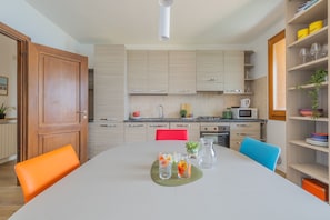 Een moderne keuken met lichte houten keukenkastjes, een eettafel met stoelen en een keukenblok met een spoelbak.