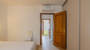 Um quarto de hotel com cama, uma cadeira, um guarda-roupa e um aparelho de ar condicionado.