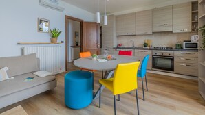 Uma cozinha moderna com armários de madeira, uma mesa de jantar com cadeiras coloridas e um forno embutido.