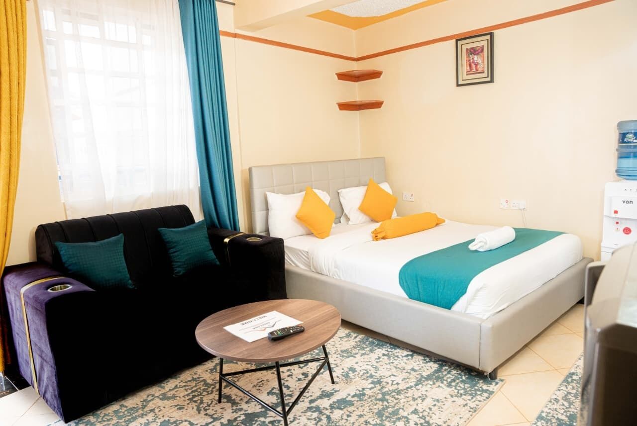 Ein Hotelzimmer mit einem Bett, einem Schlafsofa, einem kleinen Tisch und einem Wasserspender.