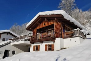 Eine Holzhütte mit Balkon, umgeben von schneebedeckten Bäumen.
