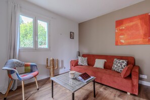 Una sala de estar con un sofá, una silla, una mesita de centro y una ventana con cortinas.