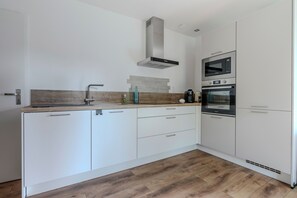 A modern kitchen with white cabinetry, a stainless steel range hood, and a built-in oven. - Holiday Home 'Mazet Avec Terrasse Et Clim' with Private Terrace, Wi-Fi and Air Conditioning (Courthézon)
