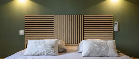 A bed with two pillows, a wooden headboard, and two wall-mounted lights.