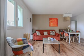 Un salon comprenant un canapé, une table basse, une table à manger avec des chaises et une fenêtre.