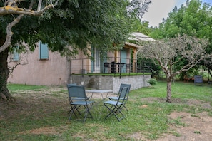 An outdoor seating area with two tables and four chairs, a small tree, and a building with a balcony. - Holiday Home 'Mazet Avec Terrasse Et Clim' with Private Terrace, Wi-Fi and Air Conditioning (Courthézon)