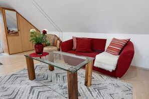 A living room with a glass coffee table, red sofa, and a mirror on the wall.