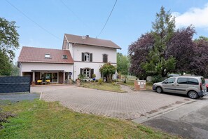 A two-story house with a tiled roof, a paved driveway, and a parked car.