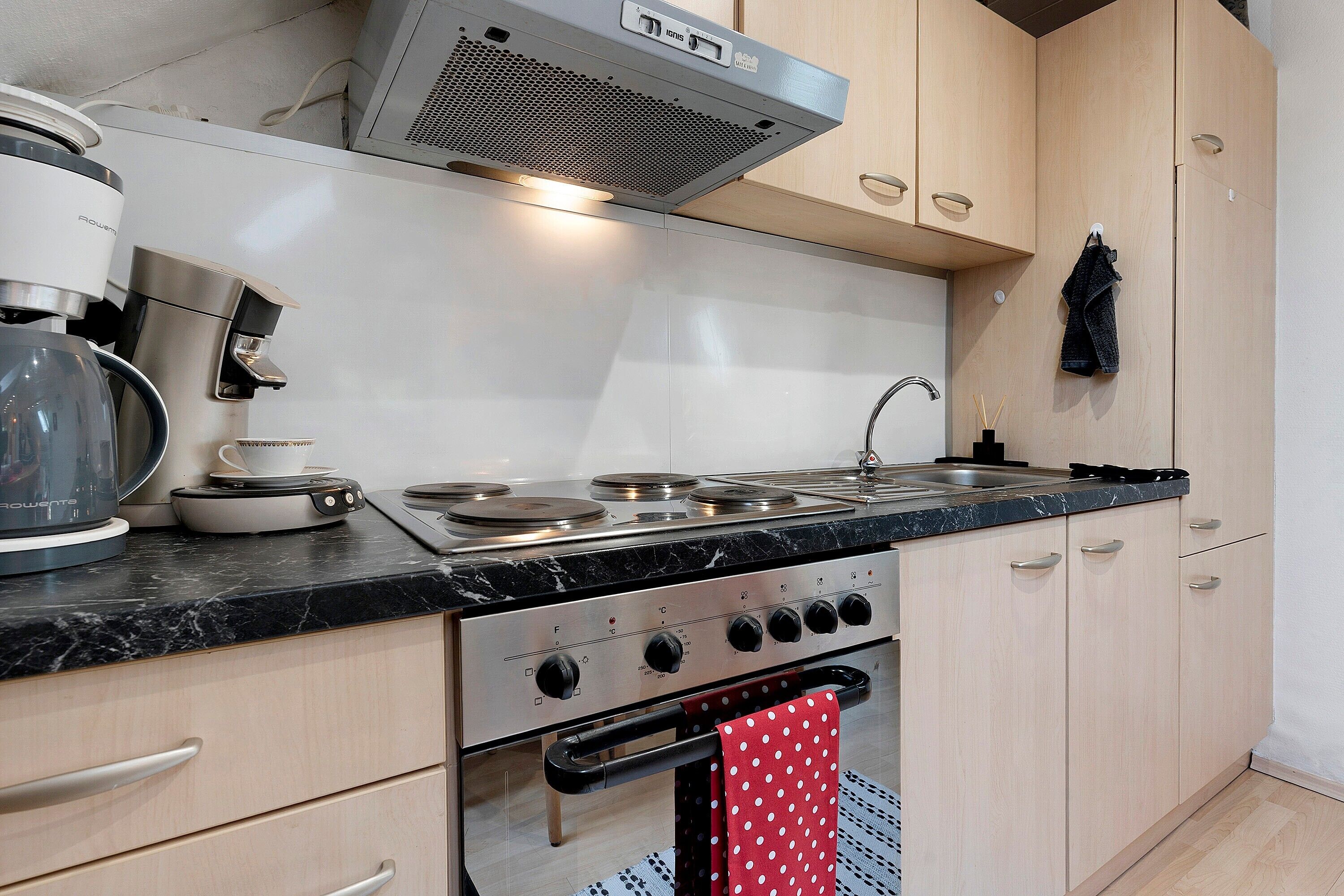 A kitchen with a stove, oven, and coffee maker.