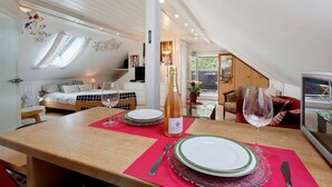En matplats med ett bord dukat för två personer, en flaska vin och utsikt över sovrummet och balkongen.