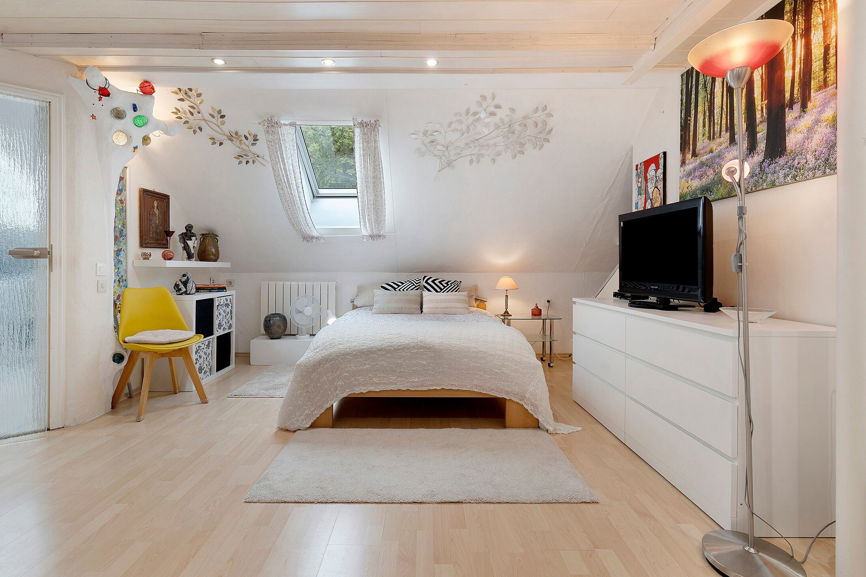 Ein Schlafzimmer mit Bett, Fernseher, Stuhl und Heizkörper.