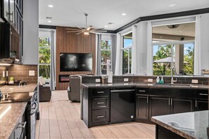A modern kitchen with a large island, built-in appliances, and a flat-screen TV. - Luxury Villa with Pool & Sports Court (West Palm Beach)