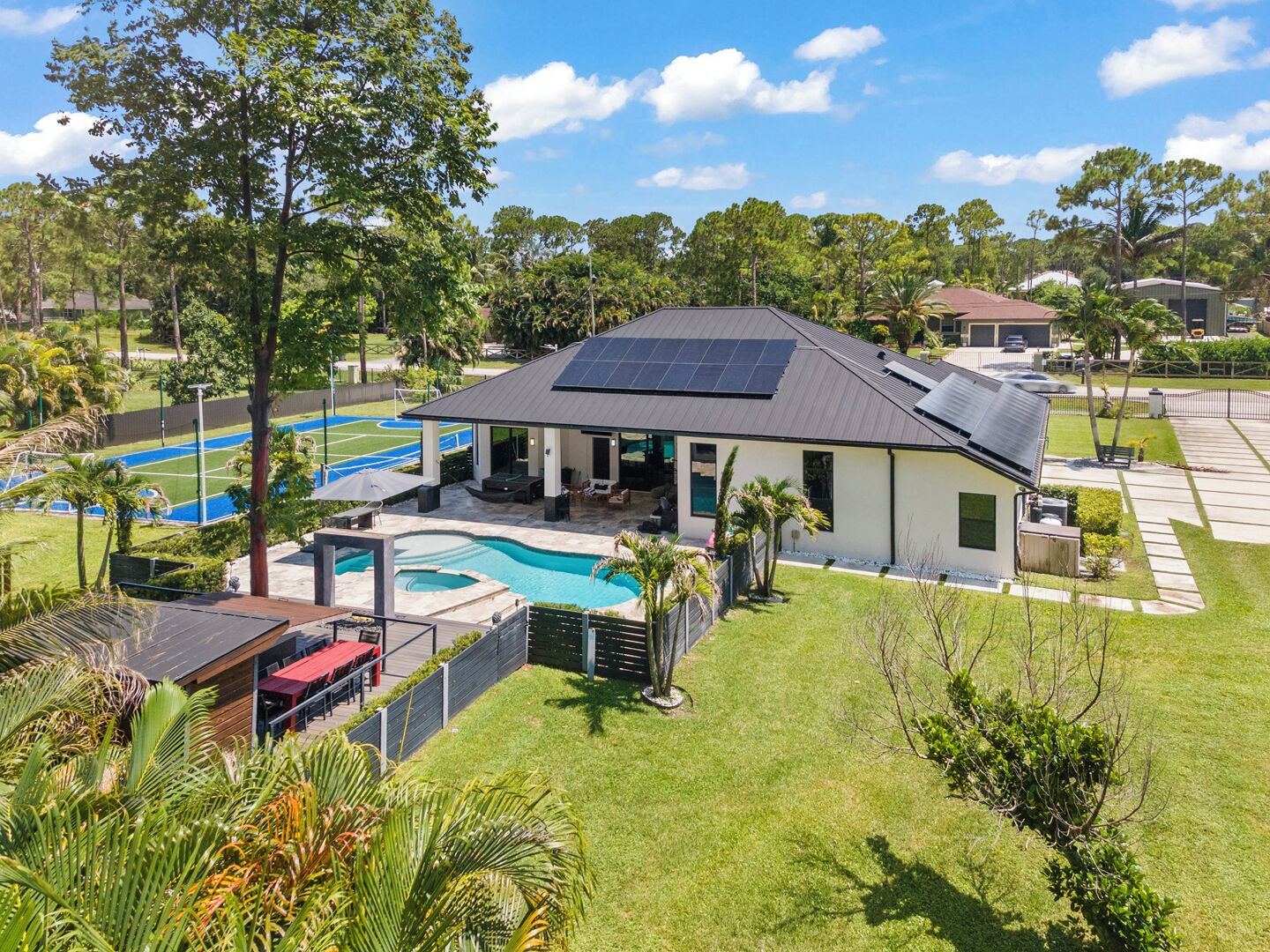 A residential property with a swimming pool, solar panels, and a covered patio area.