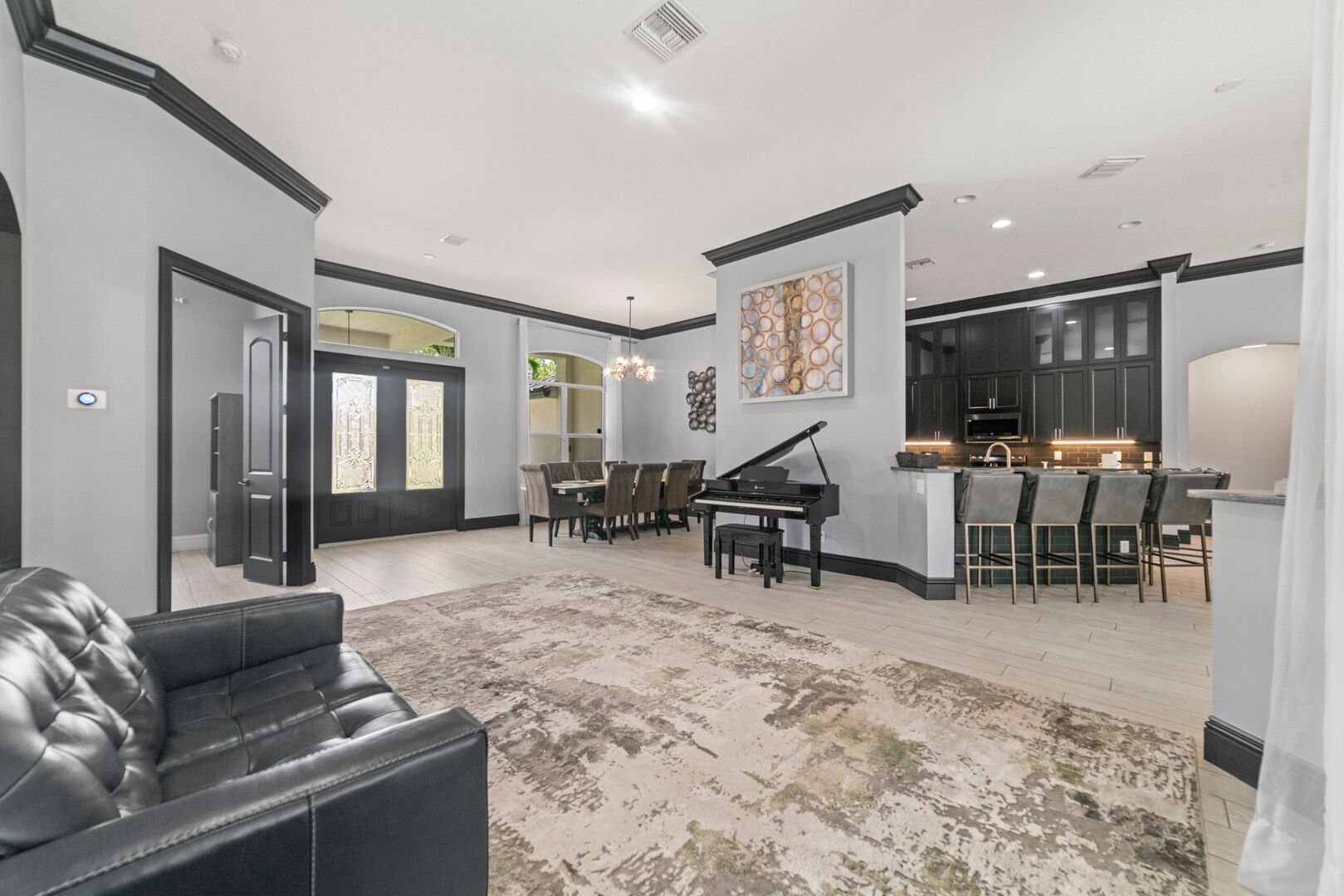 A spacious living area with a piano, dining table, and a kitchen area with bar seating.