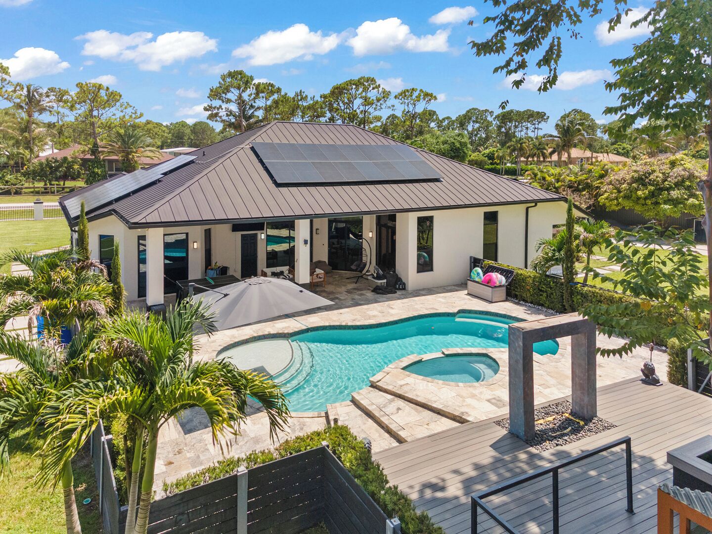 A modern house with a swimming pool, solar panels, and a deck.
