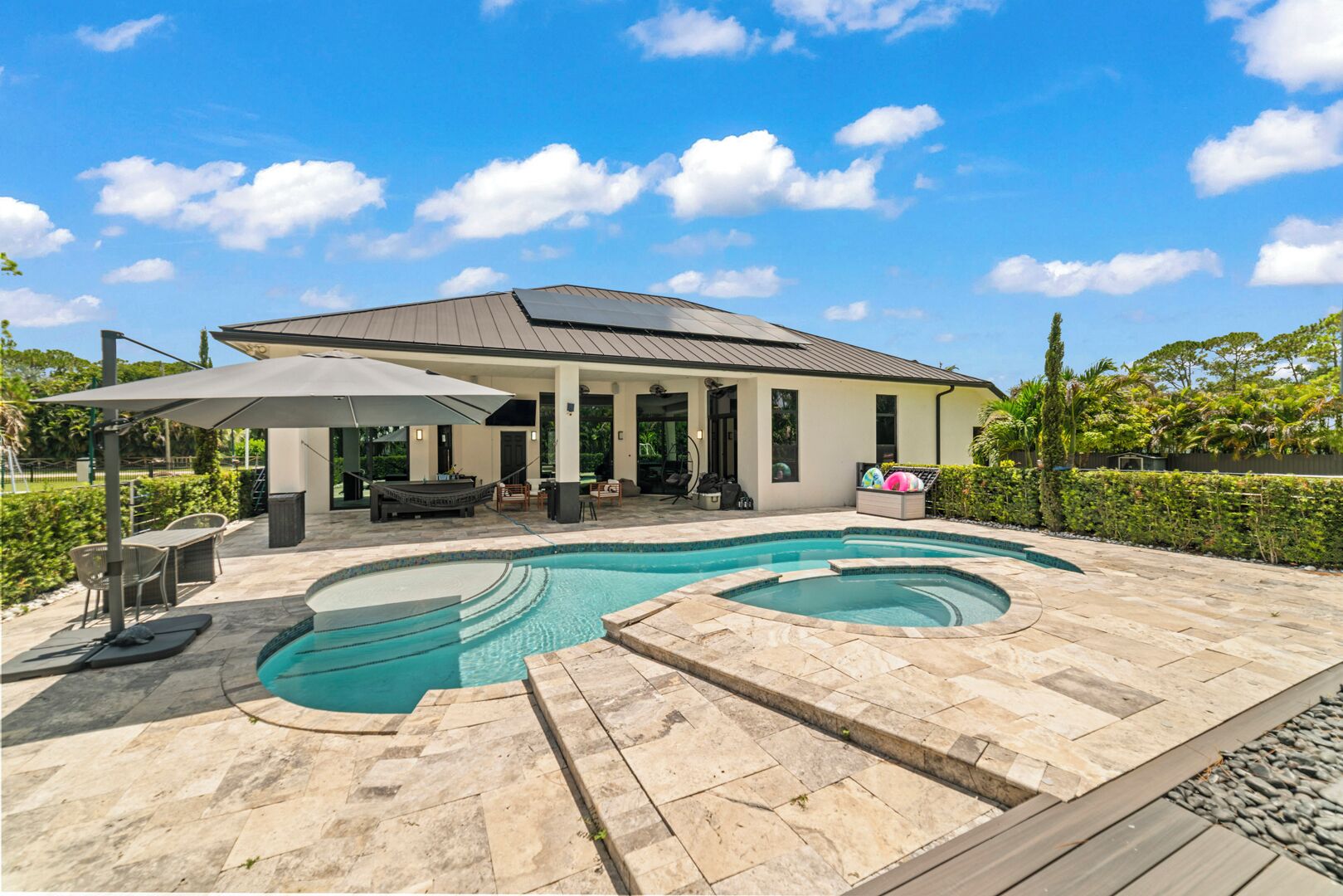 A house with a swimming pool, outdoor furniture, and a covered patio area.