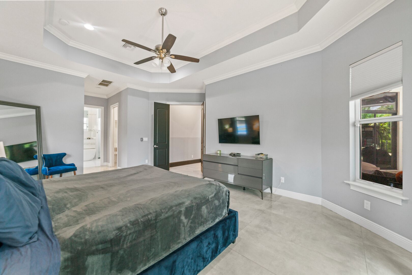 A bedroom with a bed, a dresser, a television, and a ceiling fan.