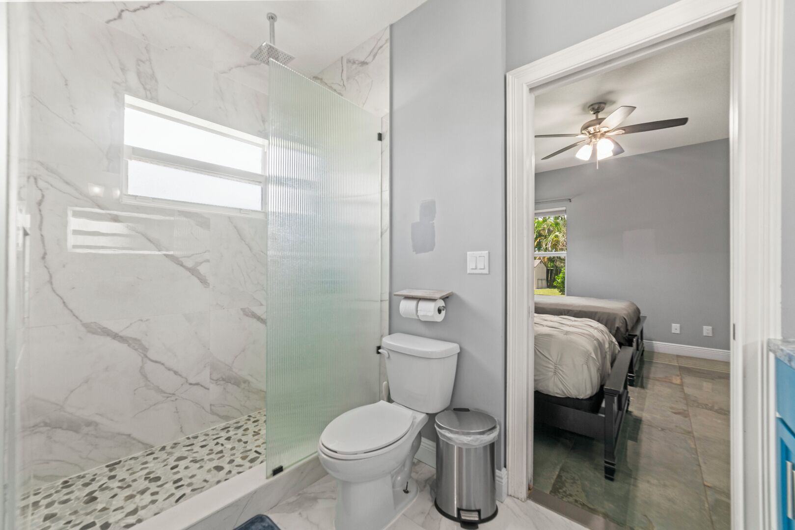 Baño con ducha, inodoro y un pequeño cubo de basura.