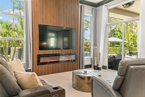 Ein modernes Wohnzimmer mit Flachbildfernseher, integriertem Kamin und einer gemütlichen Sitzecke.