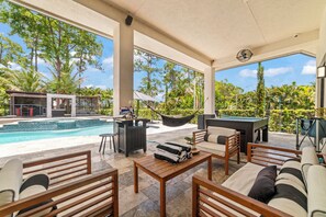 A covered outdoor area with a pool, lounge chairs, a table, and a hammock.