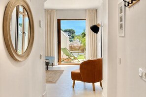 A modern interior with a large window, a round mirror, a sofa, and a lamp. - Ten Pool Apartment at Hacienda Clavero (Málaga)