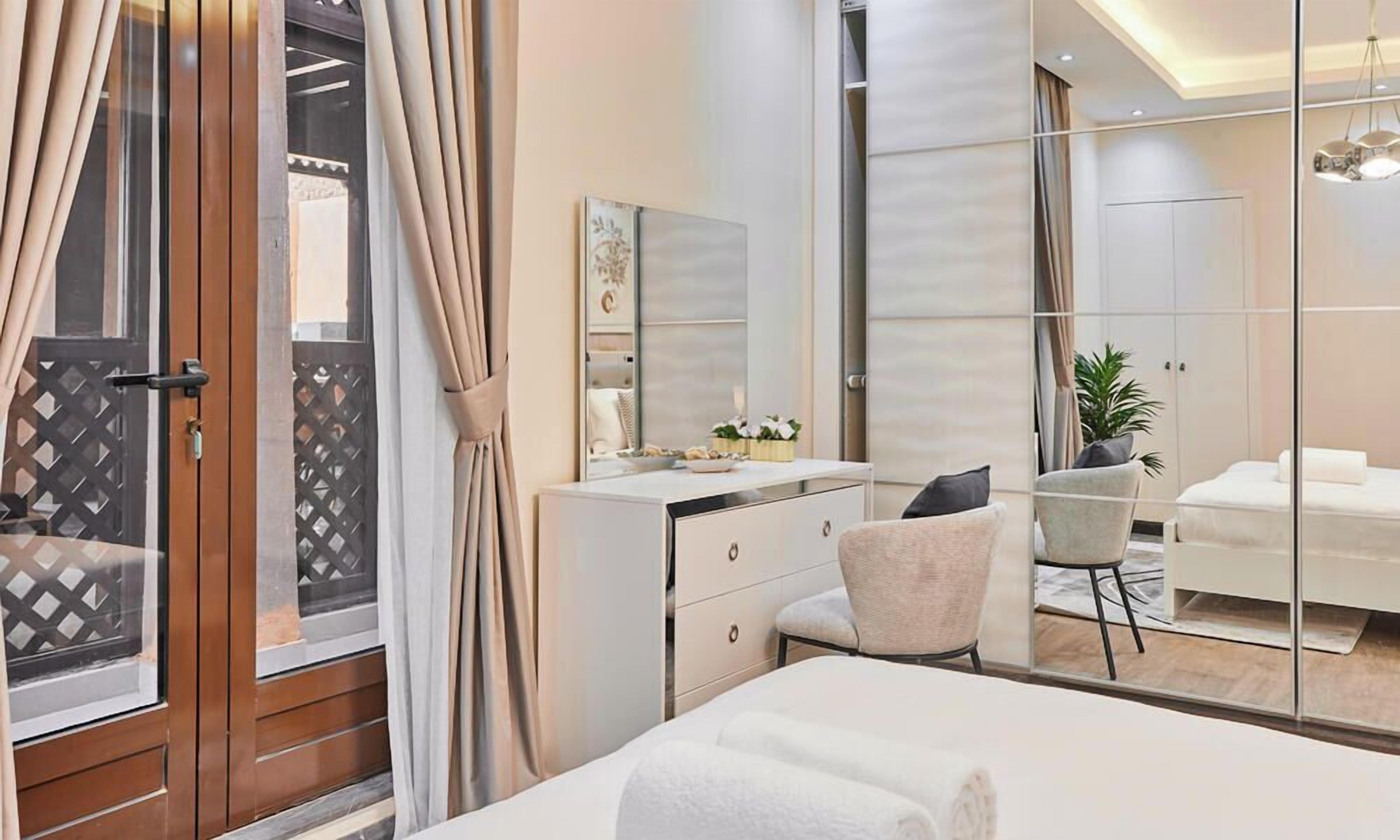 Ein modernes Hotelzimmer mit einem großen Bett, einem Schreibtisch mit Stuhl, einem Spiegel und einem Kleiderschrank.