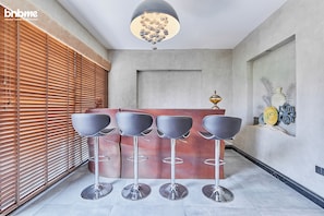 A reception area with a modern bar and four bar stools. - bnbme - Al Badia Hillside - 3B w Maids (Dubai)