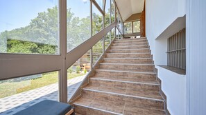 Eine Treppe mit Blick ins Freie, die zu einem überdachten Bereich mit einer Bank führt.
