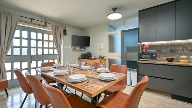 A modern kitchen with a built-in microwave, a coffee machine, and a small dining area with a wooden table and orange chairs. - Holiday Home Cerine Hill by Villas Guide (Gornji Vinkovec)