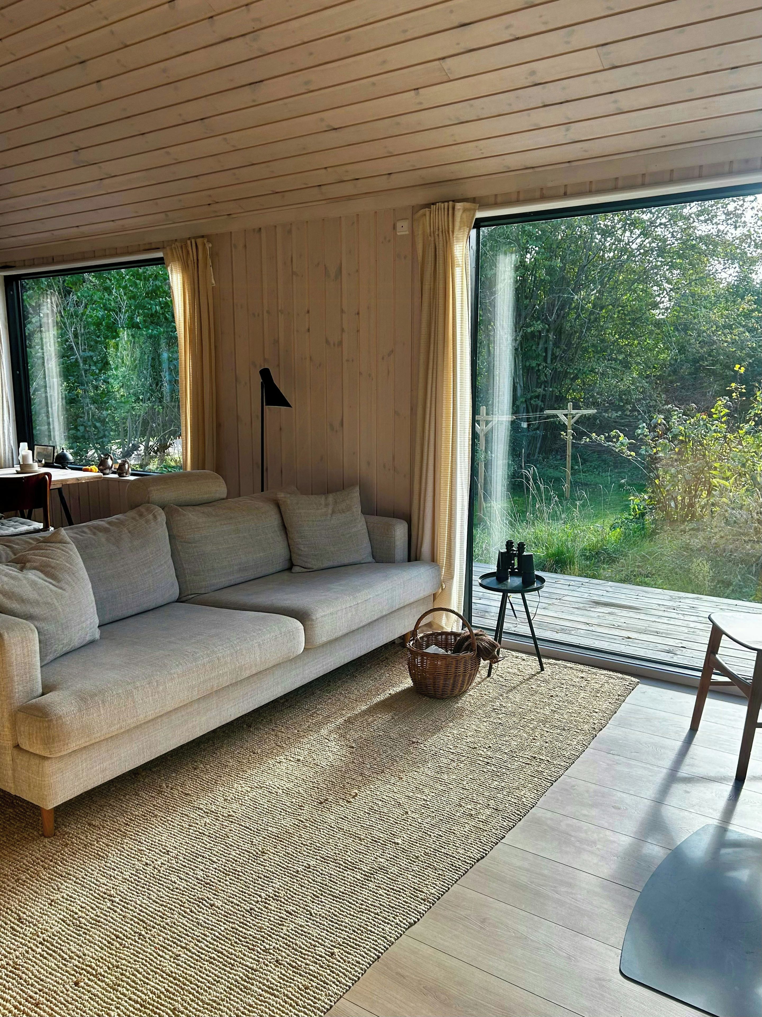 A cozy living room with a sofa, a small table, and a view of the outdoors.
