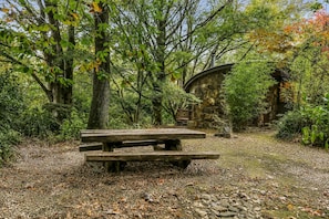 A rustic wooden picnic table surrounded by dense foliage and a stone building. - Olinda Beech 2 by Ready Set Stay (2 bedroom) (Olinda)