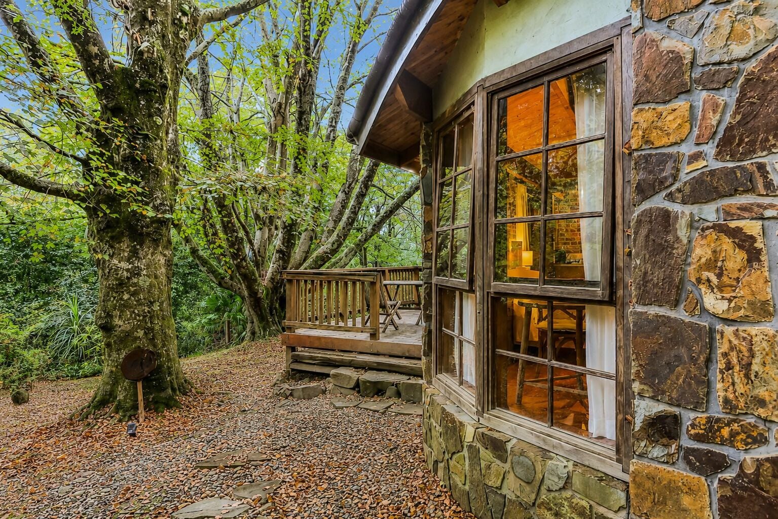 Un bâtiment en pierre doté d’une terrasse en bois et de grandes fenêtres.