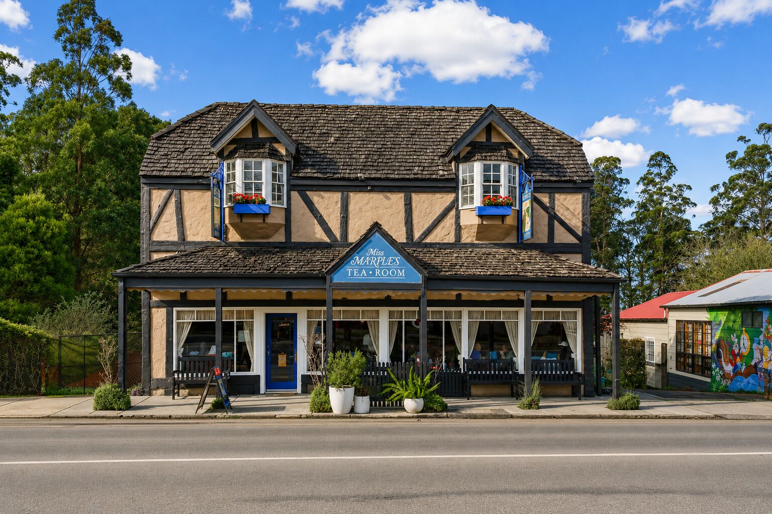 A two-story building with a sign reading 'Miss Marple's Tea Room' and a balcony with potted plants.