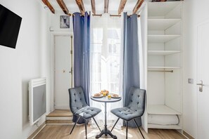 Ein kleines Zimmer mit zwei Stühlen, einem Tisch mit Frühstück und Blick durch ein Fenster.