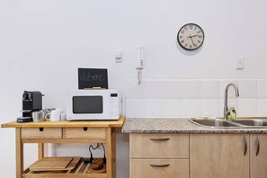 A kitchen with a microwave, coffee maker, and a clock on the wall. - Historic Merchant's Quarters West End + Parking (Fremantle)