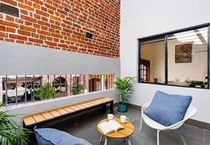 A modern interior with a brick wall, a bench, a table with a book, a chair, and a potted plant. - Historic Merchant's Quarters West End + Parking (Fremantle)