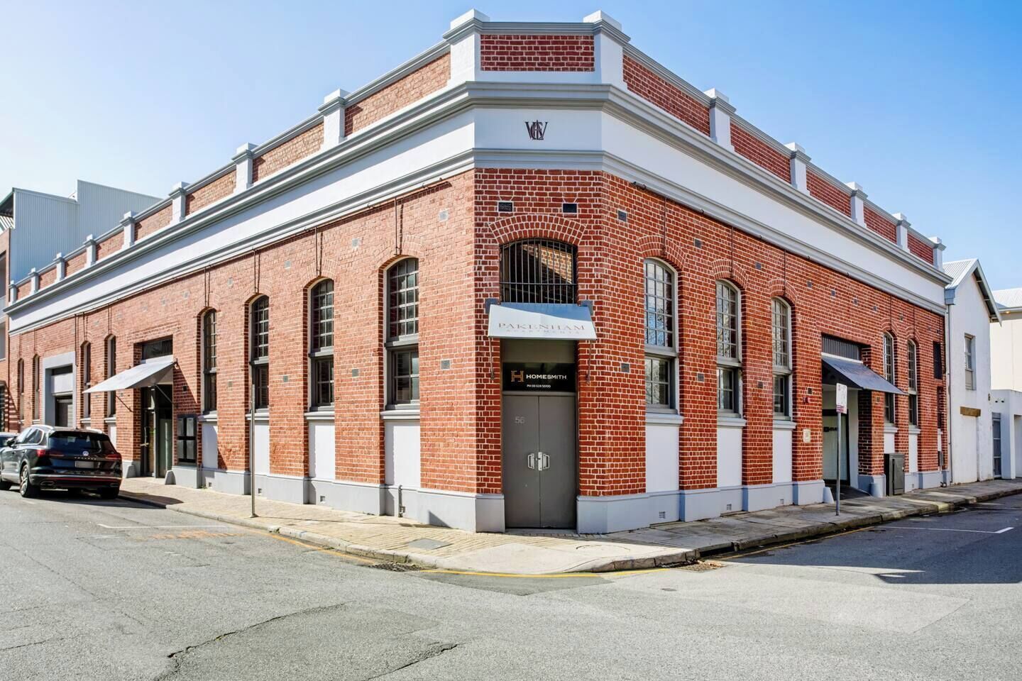 A red brick building with a white trim, a storefront, and a garage door.