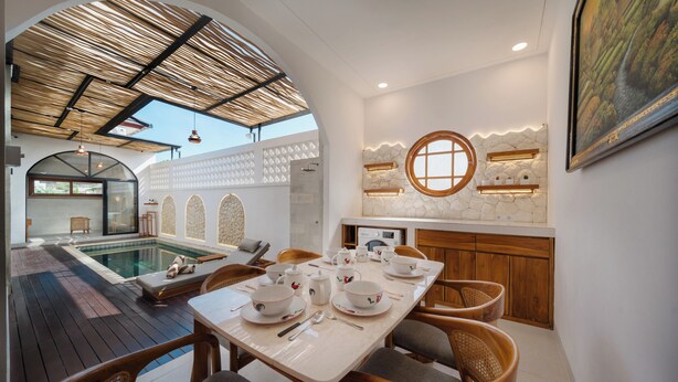 Um interior moderno com área de refeições, piscina e parede de pedra com prateleiras embutidas.