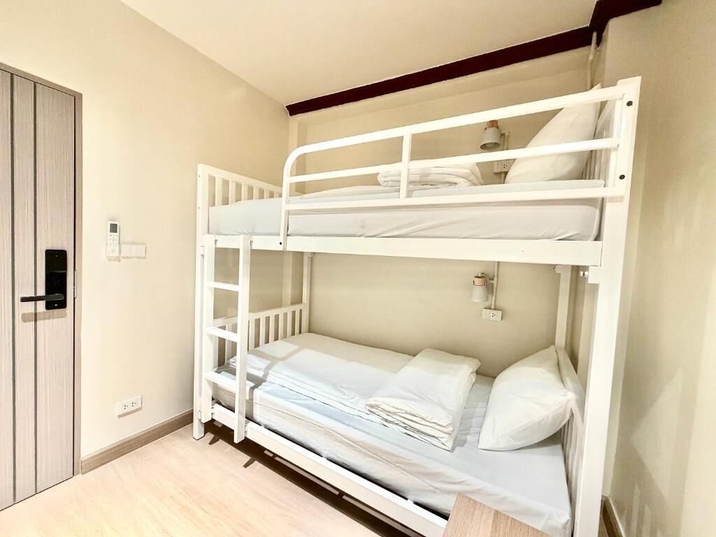 A bunk bed with a ladder, a bedside table, and a wall-mounted light fixture.