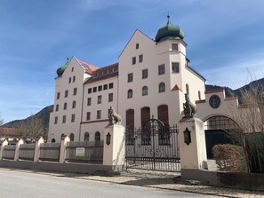 Un edificio grande e histórico con numerosas ventanas y una cúpula verde destacada.