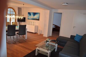 Una sala de estar con sofá, mesa de centro y comedor con sillas y una mesa.