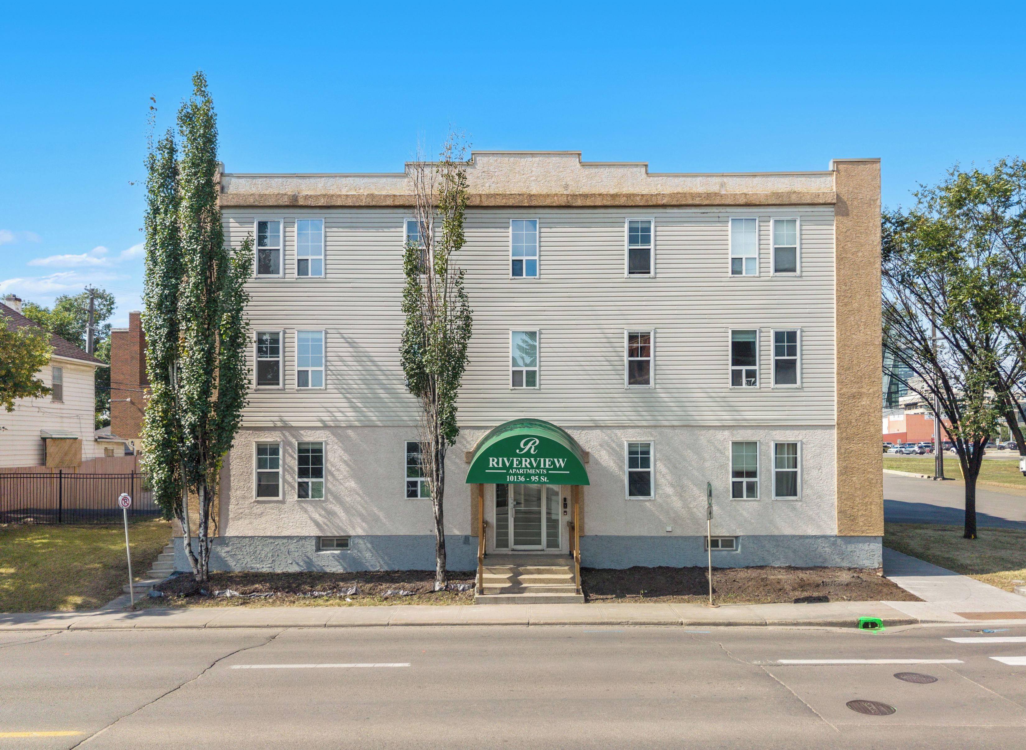 Un immeuble à plusieurs étages, doté d’un auvent vert sur lequel est inscrit le nom « Riverview Apartments ».