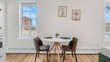 A modern room with a round dining table, two chairs, a small plant, and two framed pictures on the wall.