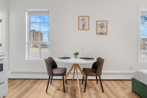 A modern room with a round dining table, two chairs, a small plant, and two framed pictures on the wall. - Edmonton Convention Centre Studio | Parking, Wifi (Edmonton)